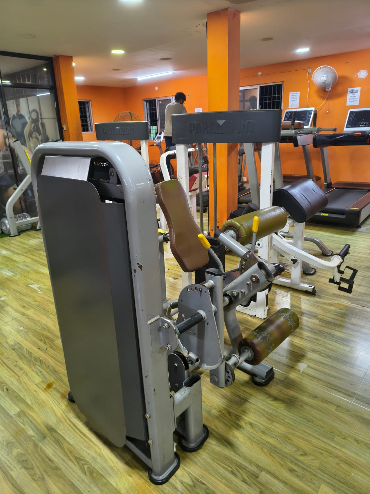 Leg extension machine with treadmills along the orange back wall of the gym