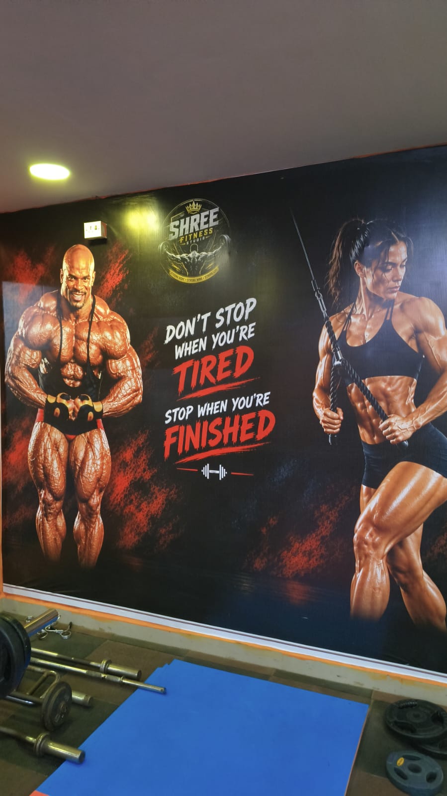Mural with the quote “Don’t stop when you’re tired” above a barbell and weight plate area