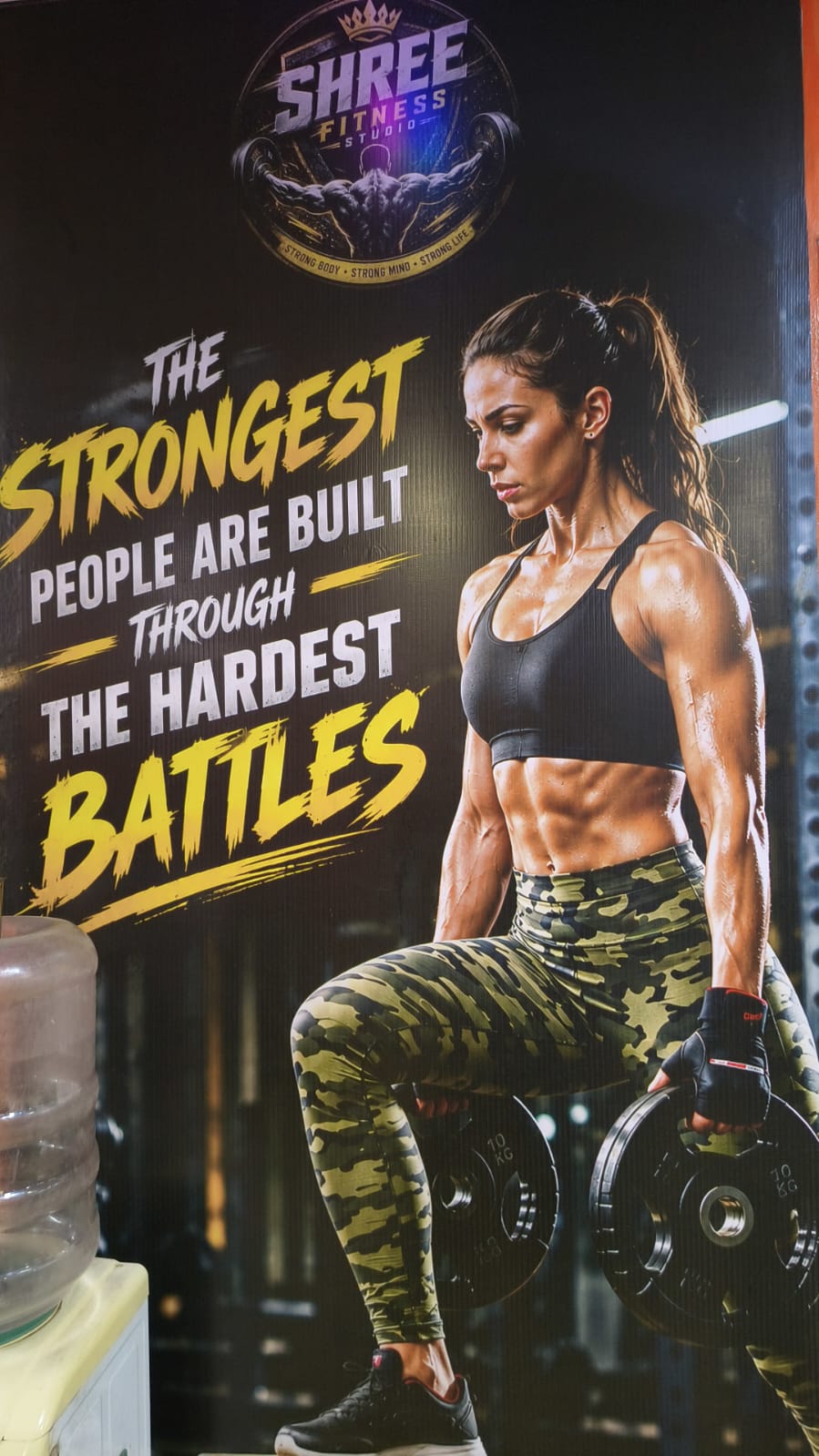 Poster of a woman holding weight plates: “The strongest people are built through the hardest battles”
