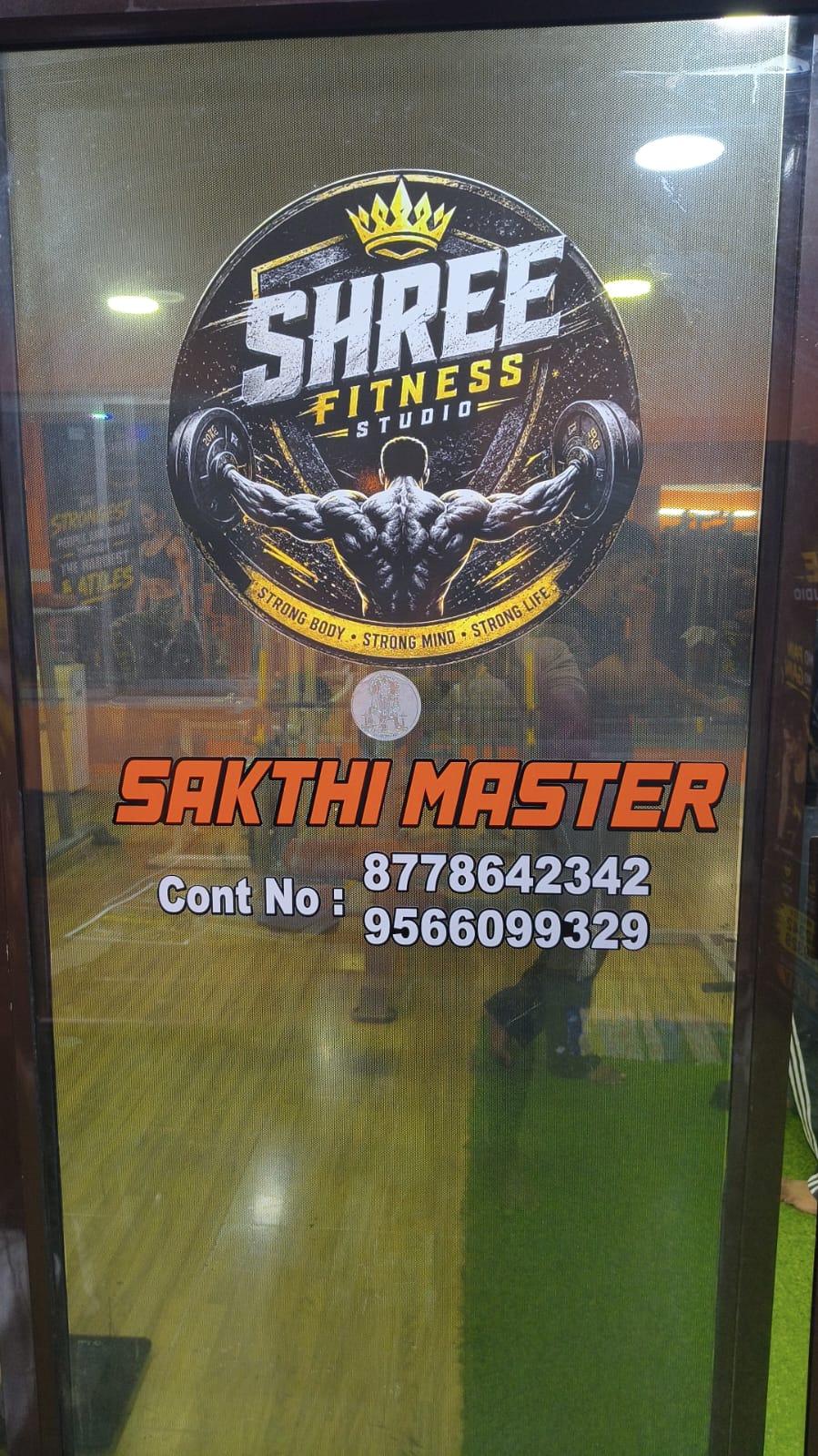 Glass entrance door with the Shree Fitness Studio crown logo and Sakthi Master’s contact numbers